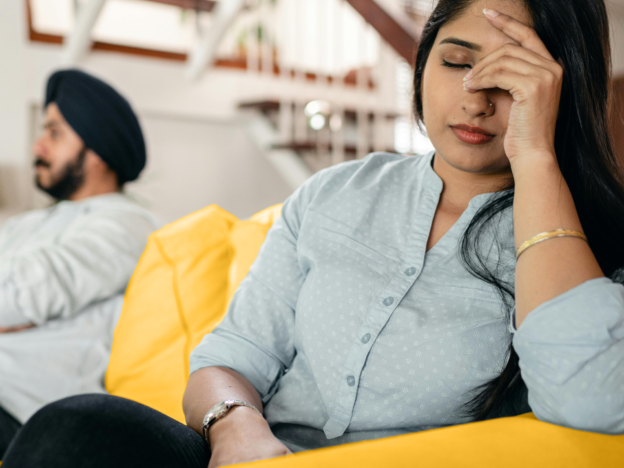 Woman sits on the couch contemplating how divorcing her husband with impact her finances