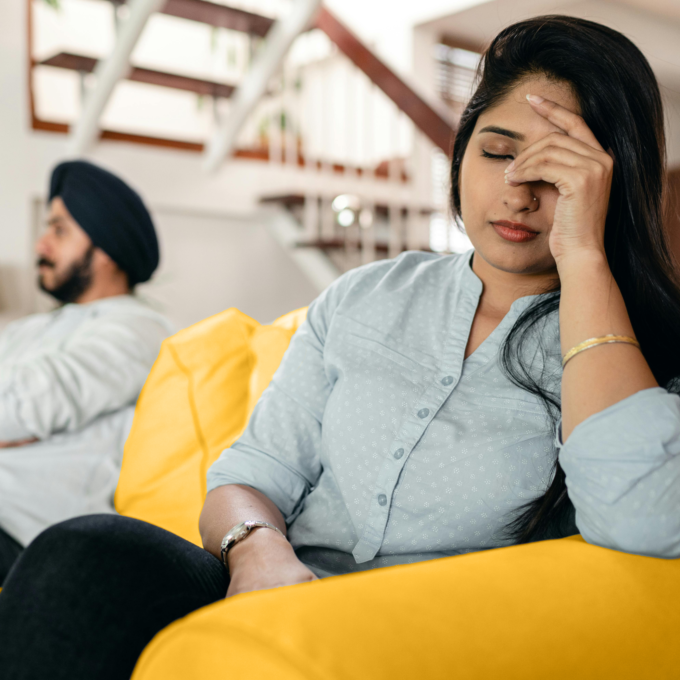 Woman sits on the couch contemplating how divorcing her husband with impact her finances