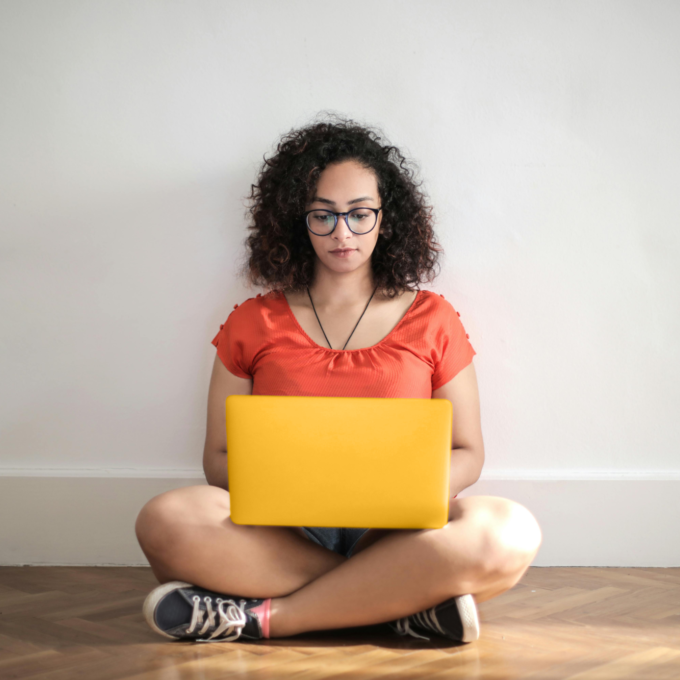 Woman sitting on floor using laptop to research how to improve credit score