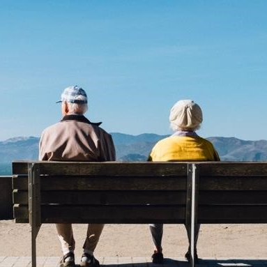 Senior couple living on a fixed income sitting on a bench overlooking mountains