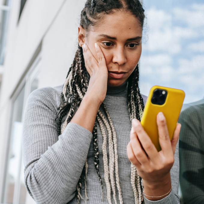 Woman nervously looking at phone receiving a collection call