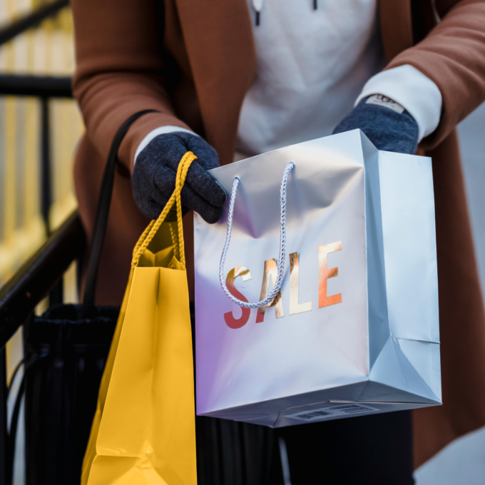 Person holding shopping bags after splurging on a sale