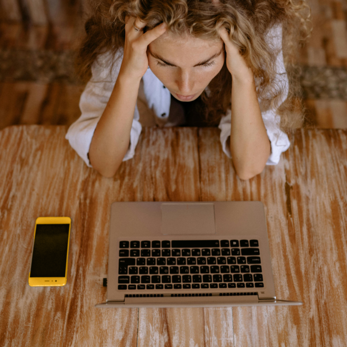 Woman sitting at a table stressed about financial situation after spotting debt warning signs