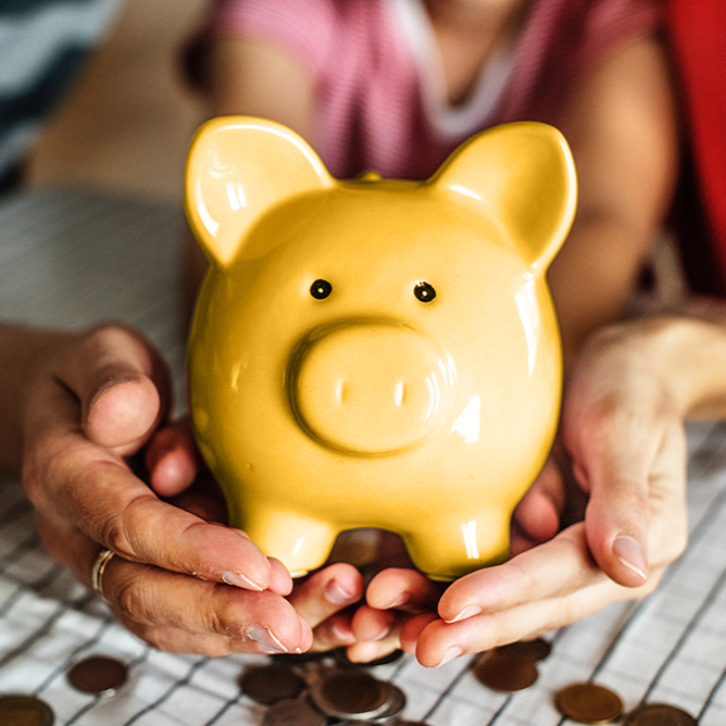 Two hands holding a yellow piggy bank, symbolizing the importance of financial goal setting