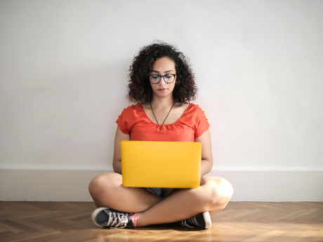 Woman sitting on floor using laptop to research how to improve credit score