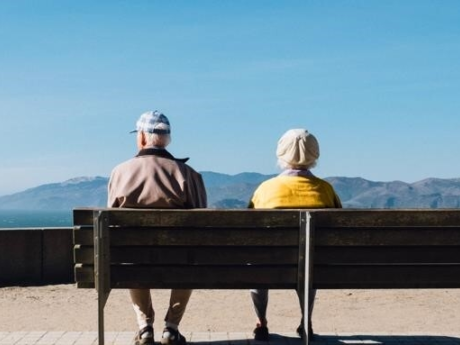 Senior couple living on a fixed income sitting on a bench overlooking mountains