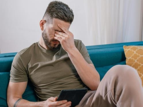Newly unemployed man sitting on sofa stressed about his financial situation