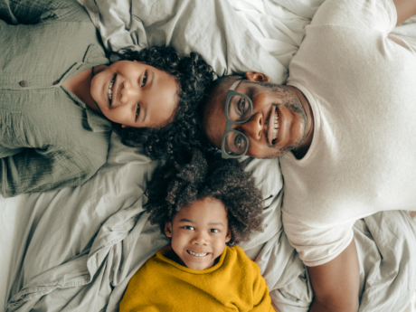 Father and two kids lying down and smiling after family financial meeting