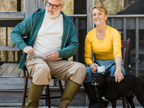 Retired man and woman sitting outside with two pet dogs