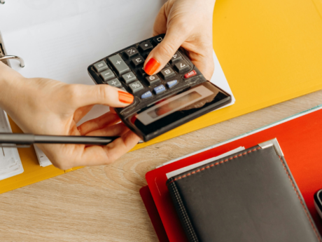 Person holding calculator while creating a basic budget