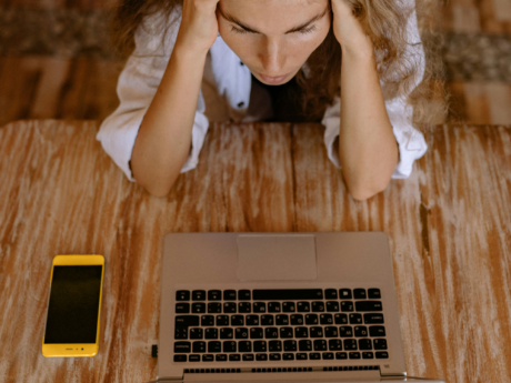 Woman sitting at a table stressed about financial situation after spotting debt warning signs