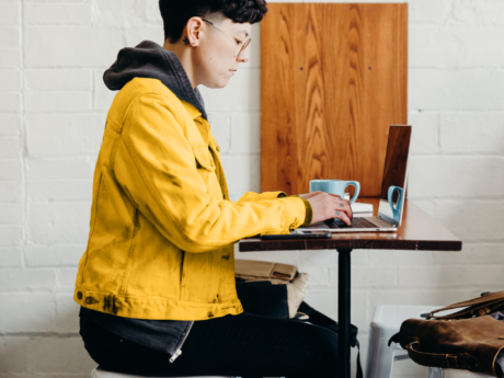 Self employed person seated at a table using a laptop doing taxes