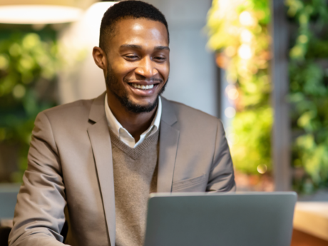 Man sitting at a desk with a laptop smiling