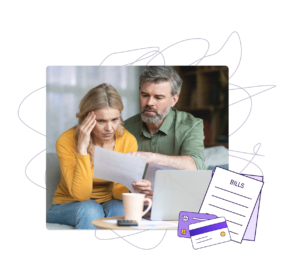 A man and a woman sitting on the couch with financial documents and a laptop looking distressed.