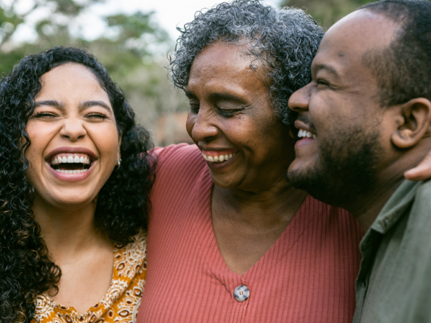 Photo of parents and adult daughter hugging and smiling.