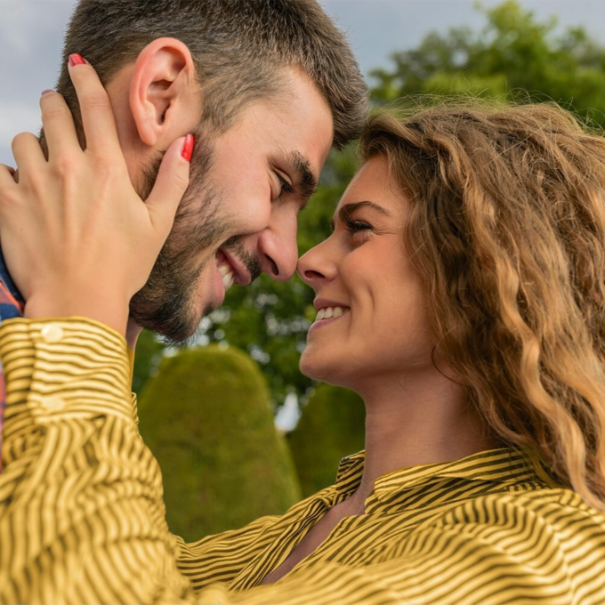 A man and woman hugging and smiling outside surrounded by trees