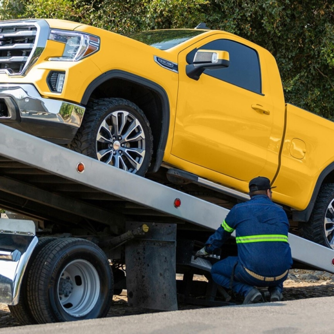 Yellow pickup truck being put on a tow truck