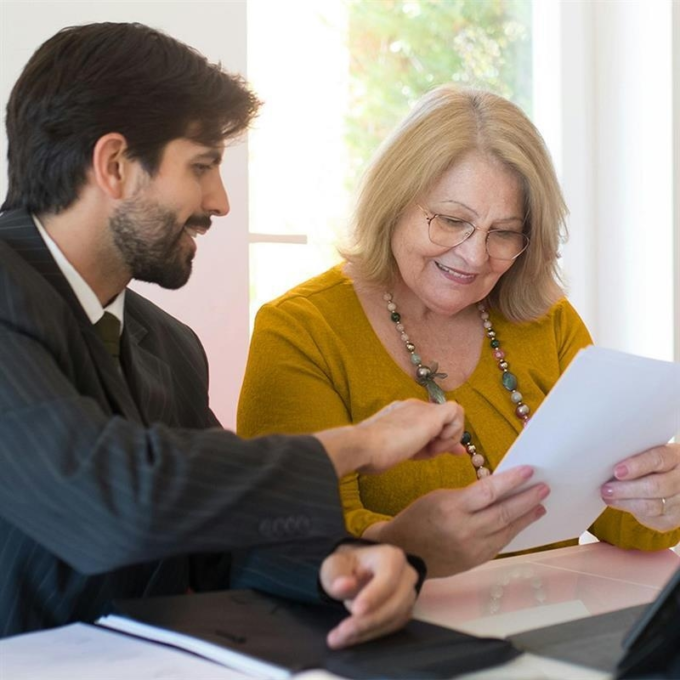 Man and woman sitting together, smiling, looking at paperwork