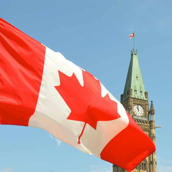 Canadian flag waving in front of the Parliament Building on Parliament Hill in Ottawa.