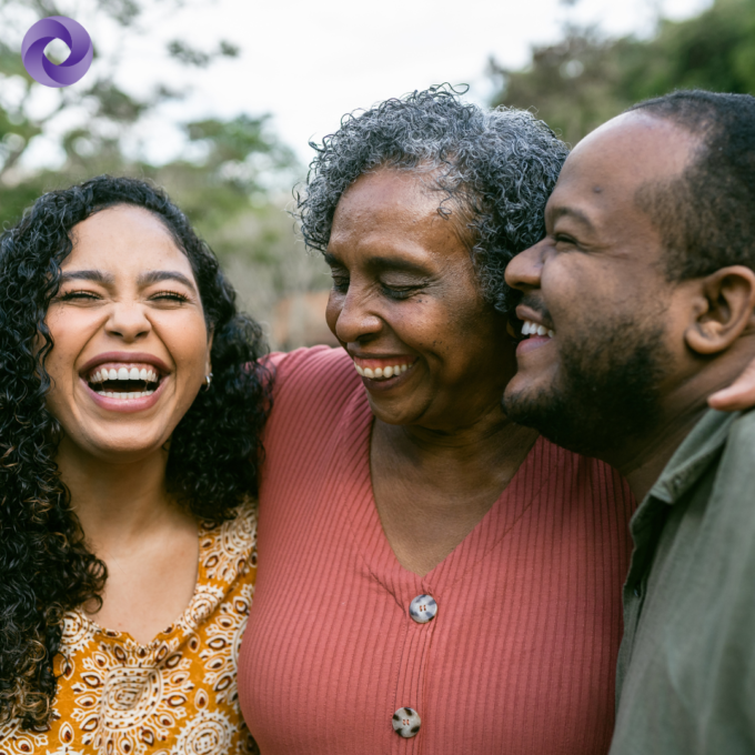 Photo of parents and adult daughter hugging and smiling.