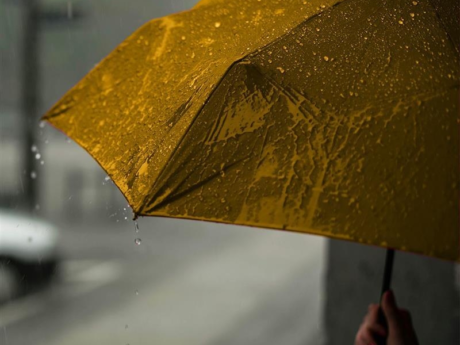 Person holding a yellow umbrella while walking down the street on a rainy day.