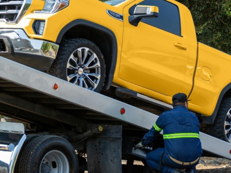 Yellow pickup truck being put on a tow truck