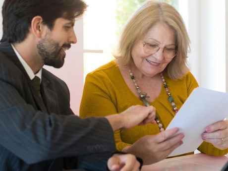 Man and woman sitting together, smiling, looking at paperwork