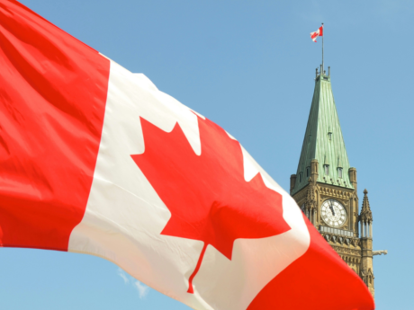 Canadian flag waving in front of the Parliament Building on Parliament Hill in Ottawa.